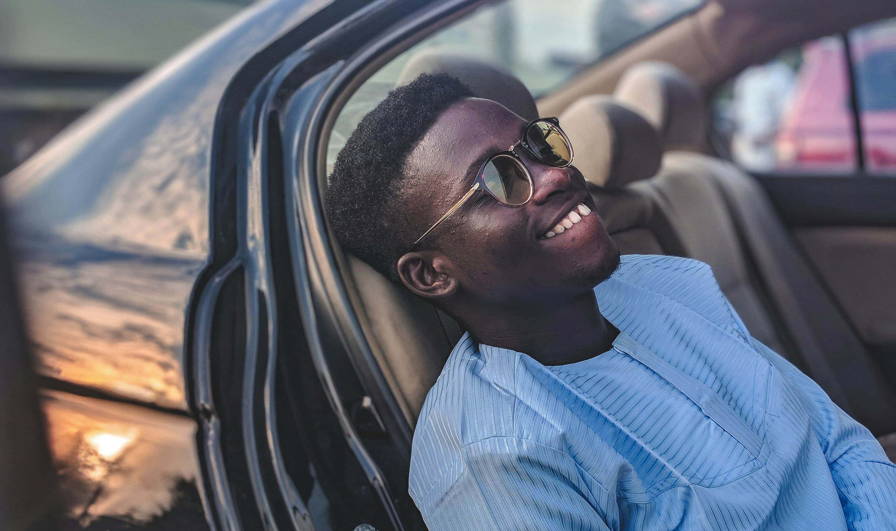 Chauffeur souriant au coucher de soleil dans son vehicule